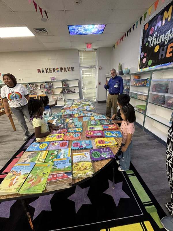 Preschool students choosing books with help from volunteers