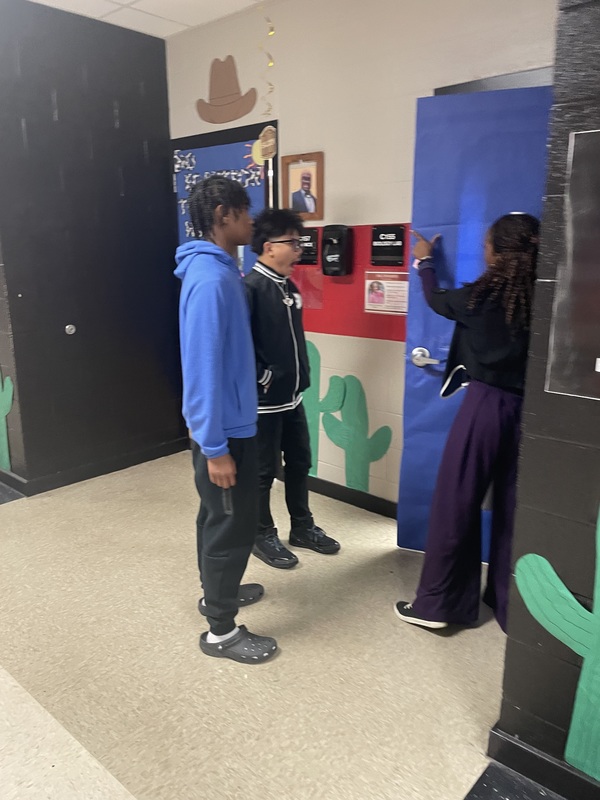 Teacher showing students how she wants door decorated for homecoming week
