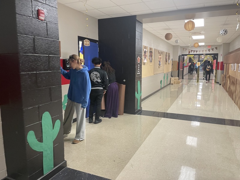 Students in hallway decorating for homecoming week with green cactus on wall
