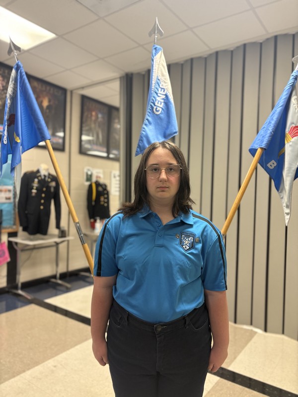 Katherine Thames, the student of the month, stands in front of flags.