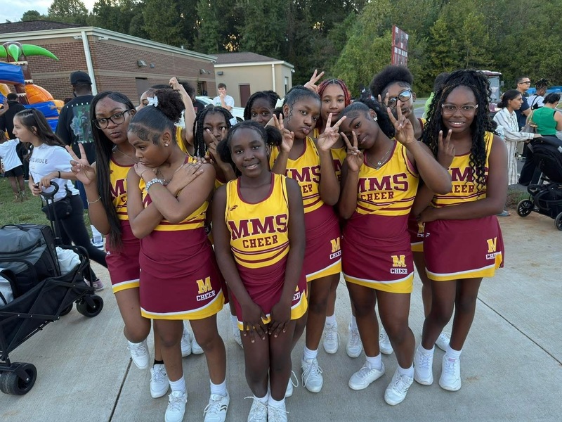Cheerleaders posing in crimson and gold uniforms at the Spirit Night on campus