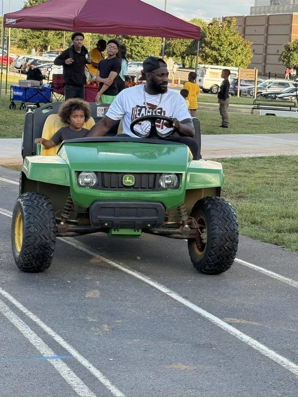 Football Coach Sammie Coates riding on track in golf cart with son during Spirit Night