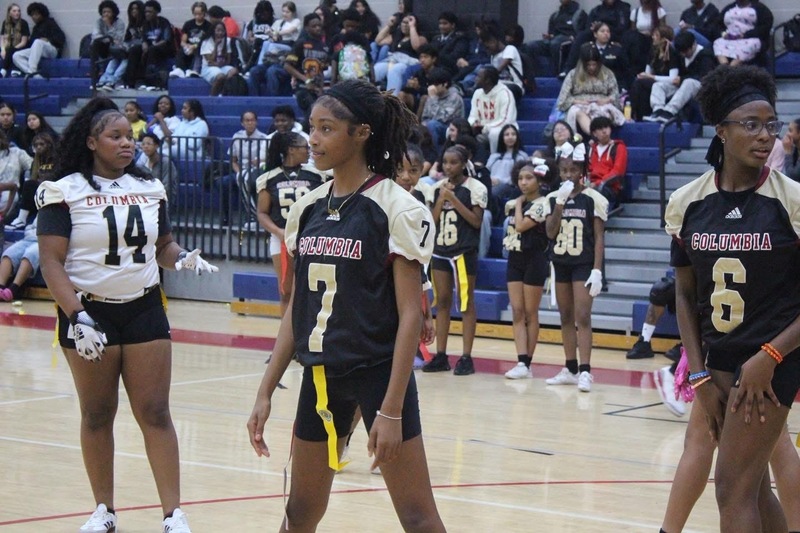 Girls in gym at Columbia with Columbia shirts on playing flag football during Powderpuff game in gym