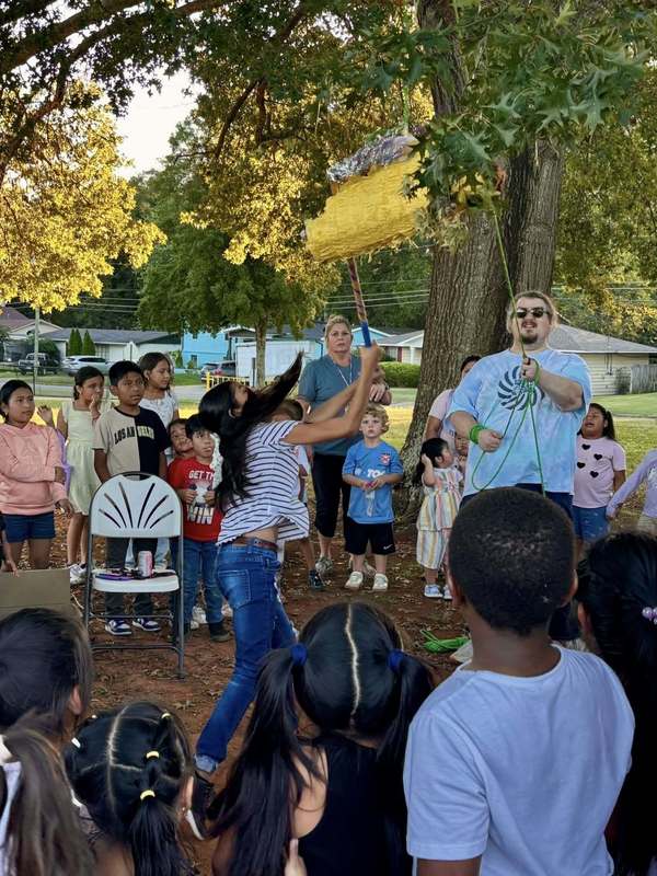 Student breaking the taco pinata as a crowd of students waits to grab candy.