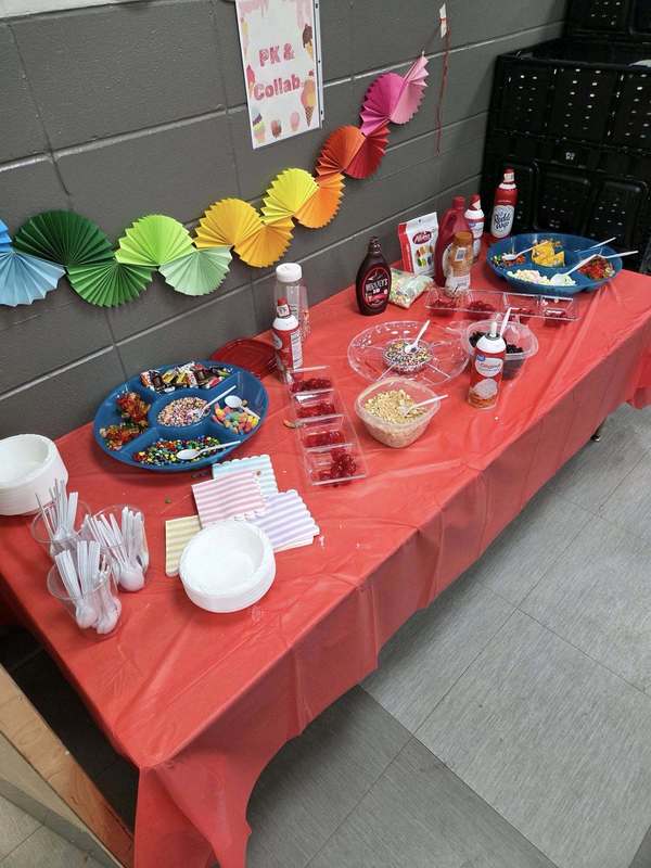 Sundae Bar Setup with decorations, toppings, whipped cream, bowls, napkins, and spoons.