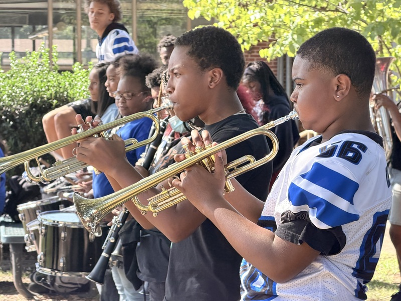During the pep rally, trumpet players are entertaining the crowd during the pep rally.