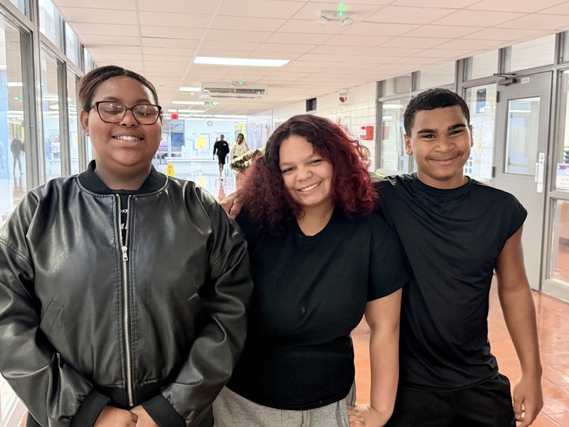 Three students are gathered together in the hallway as they enter the perfect attendance celebration. Their smiles share their excitement!