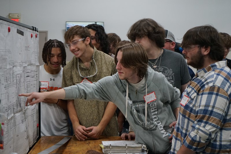 Welding and precision machining students look at a diagram of a machine at Bruderer Manufacturing Inc.