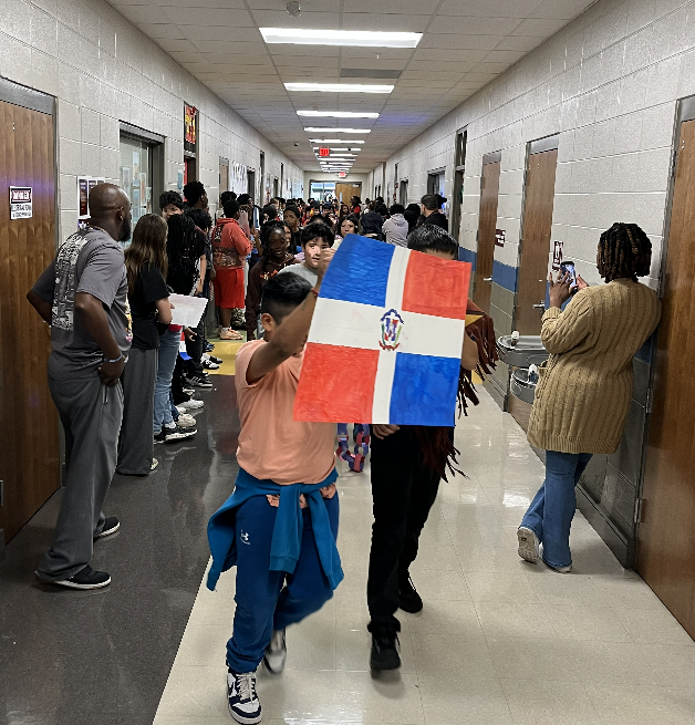 Students parade down the hall waving  the flags of Latin countries. 