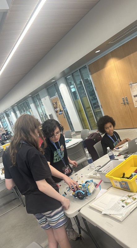 Participants from Lego League team engaged in teamwork on a Lego League project during Build Day in a spacious room.
