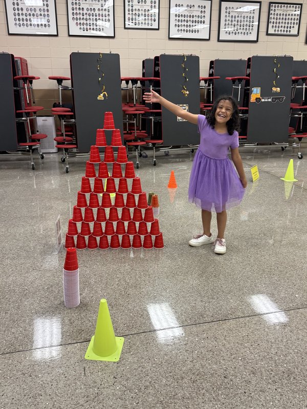 Third grader, Mary Burke, built a tall pyramid using cups.