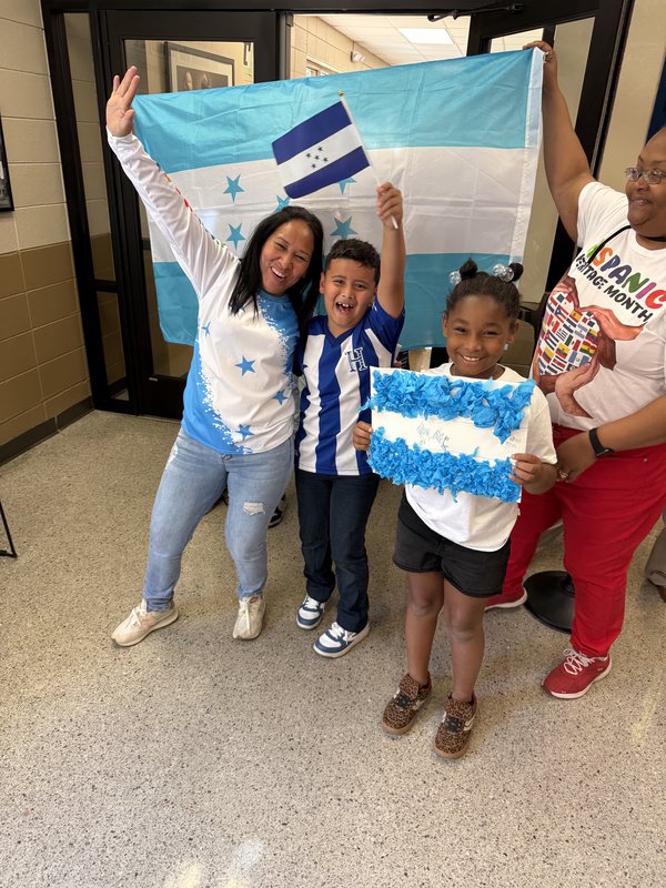 3rd grade students representing their country, Honduras, by holding up a real Honduras flag along with a mini Honduras flag.