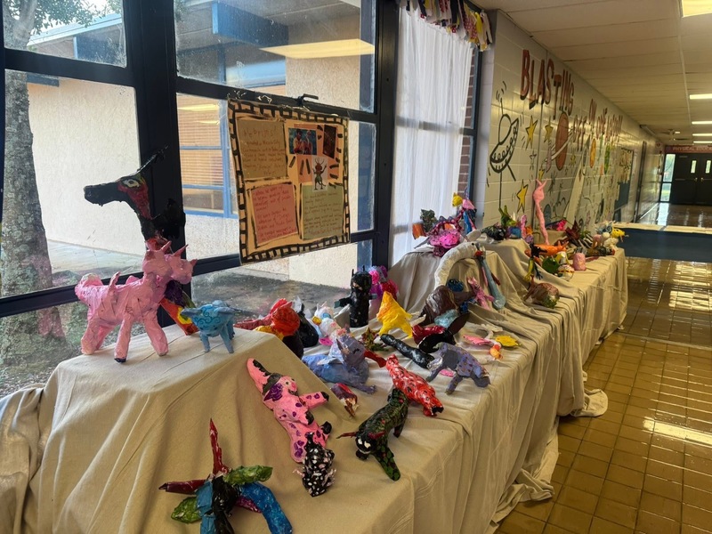 A colorful display of paper animals arranged along a hallway, showcasing various shapes and sizes