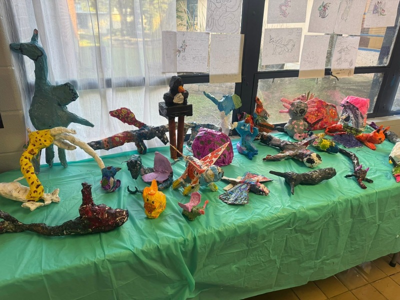 A collection of diverse animal sculptures arranged on a table, showcasing various artistic styles and details