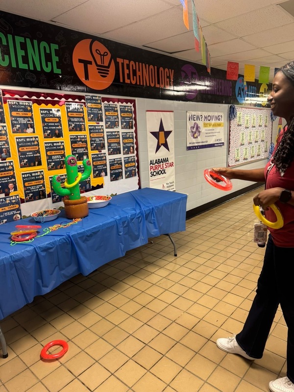 A teacher plays frisbee in hallway, promoting fun and engagement during Hispanic Heritage night activities.