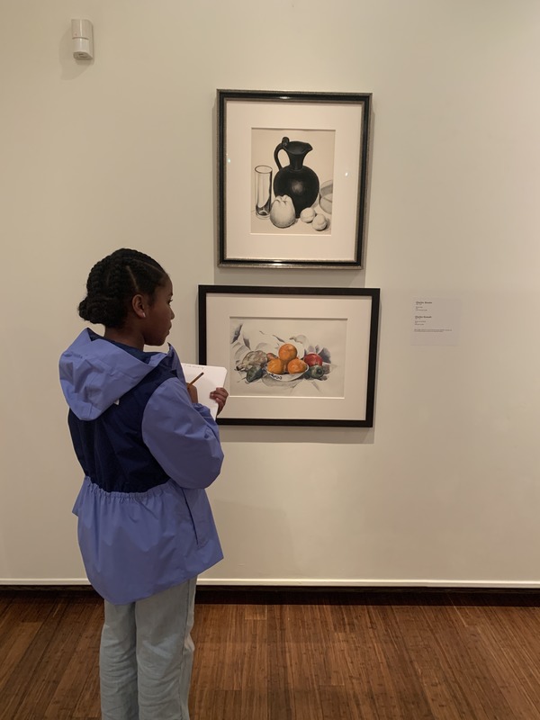 A young girl stands in front of a painting, captivated by the artwork on display