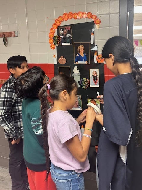 Students adding photos and items to their ofrenda.