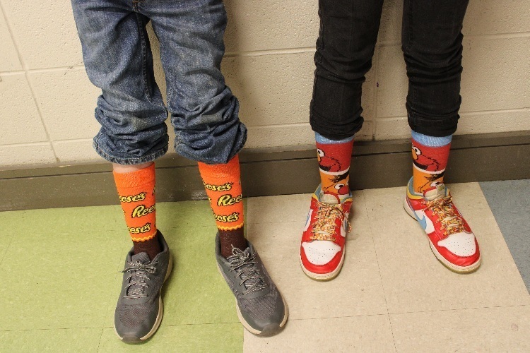 Close up of silly socks - a pair of orange Reese's cups socks and a pair of Elmo socks