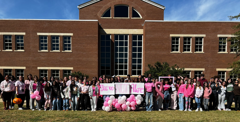 Students and faculty pose in pink for breast cancer awareness.