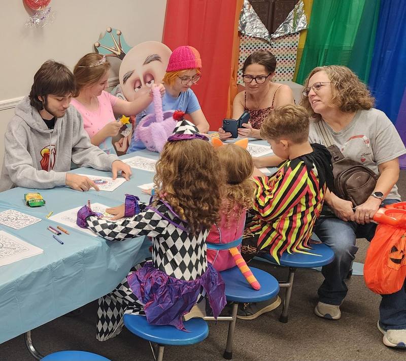 Students, 2 parents and 1 esports members at table with blue cloth and white coloing sheet coloring