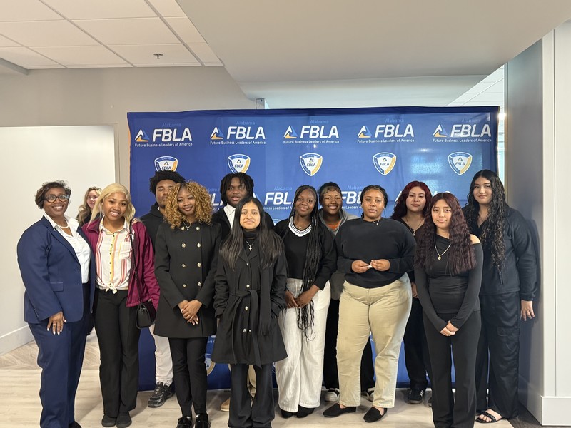 Ms. Holman standing on left blue suit and white shirt and 11 students from FBLA standing posing for the picture