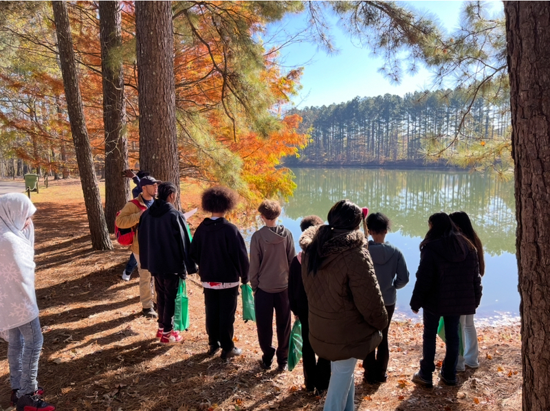 Students gather around the edge of a lake