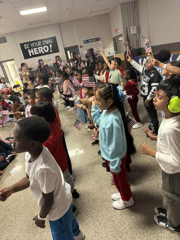 First graders seeing "3 Cheers for the Red, White, and Blue" while holding up their little American Flags.