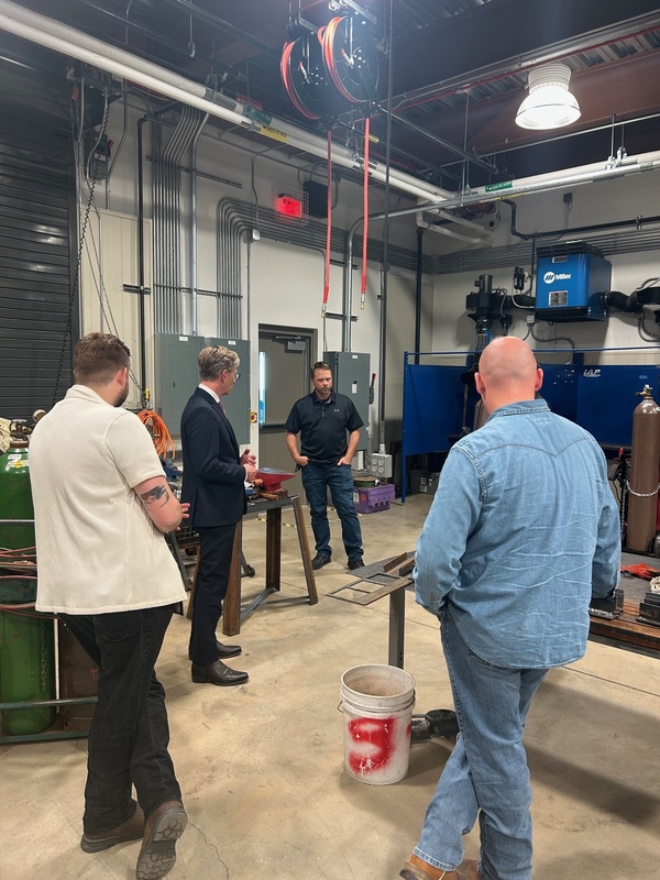 Dr. Mackey, with three instructors from Huntsville Center for Technology standing inside of the welding shop.