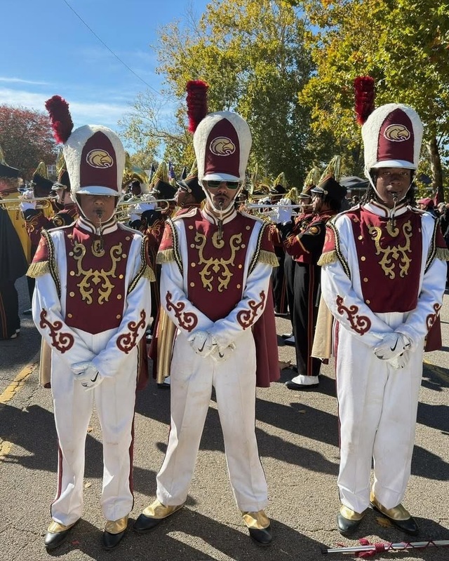 Three Band members from  Columbia High in Maroon, gold and white uniforme with hats leading the band in downtown parade for Vet's Day