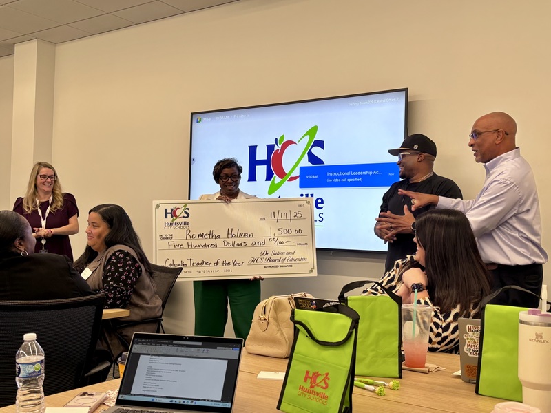 Teacher of the ear holding large check for 500 dollars