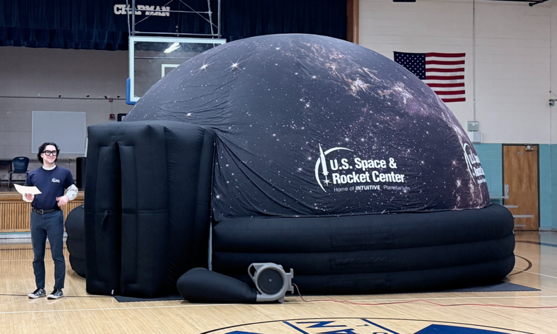 A picture of the portable planetarium fand one of the instructors set up in the gym.