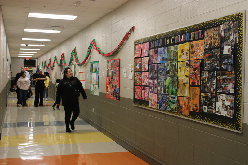 Families enjoying student artwork as they walk down the hall 