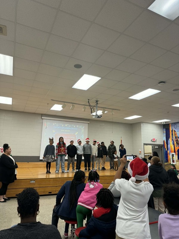 5th grade students are on the stage singing "We Wish You a Merry Christmas."