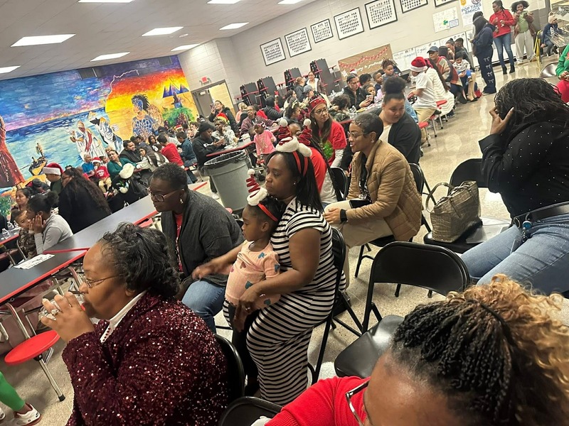 A snapshot of the cafeteria with everyone watching and enjoying their pizza.