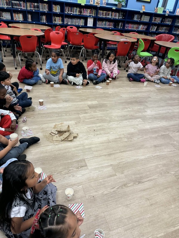 1st graders decided to sit in a circle while drinking their hot chocolate and eating their cookie.