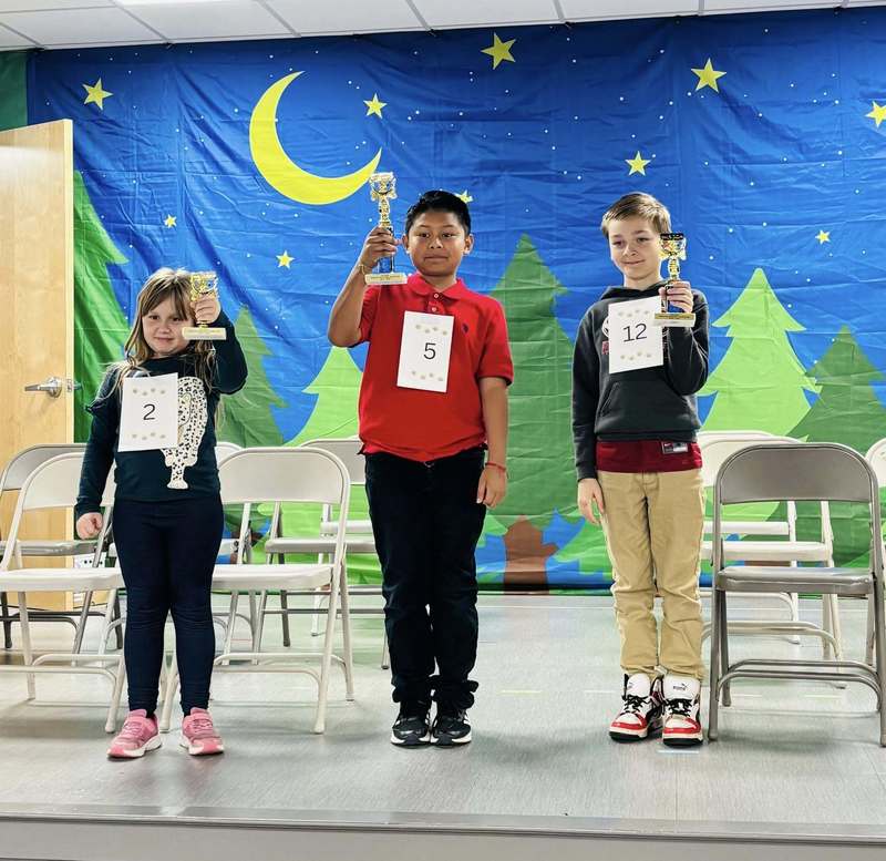 Our spelling bee finalists showing off their trophies on stage.