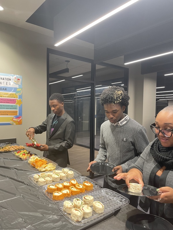 2 students and 1 parent fixing food at the banquet