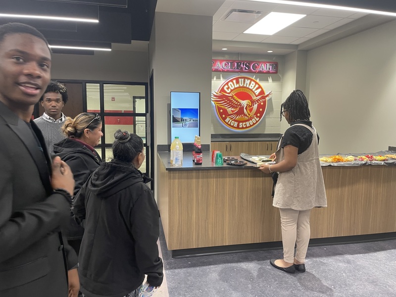 5 students standing and one with putting food on a plate
