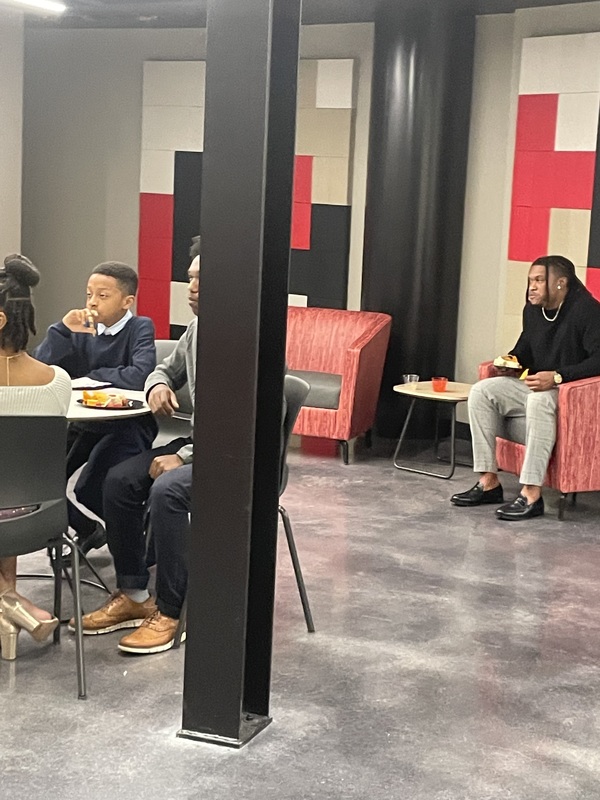 # students sitting at table and with one adult sitting in back