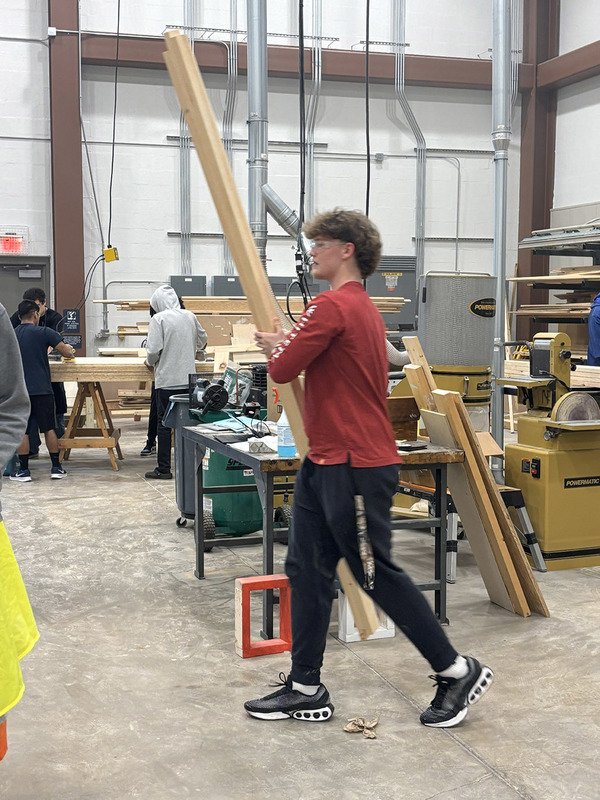 A student walks across the shop with boards in hand