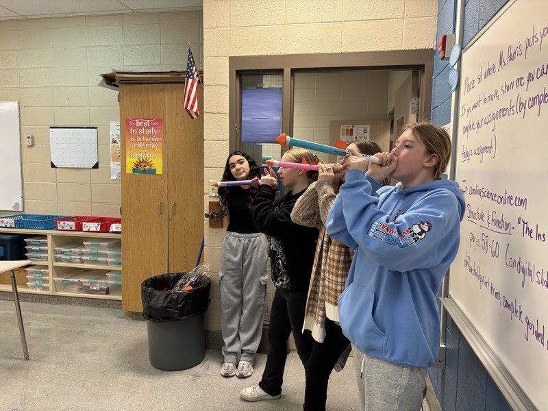 Four students launching their rockets after building them in science class.