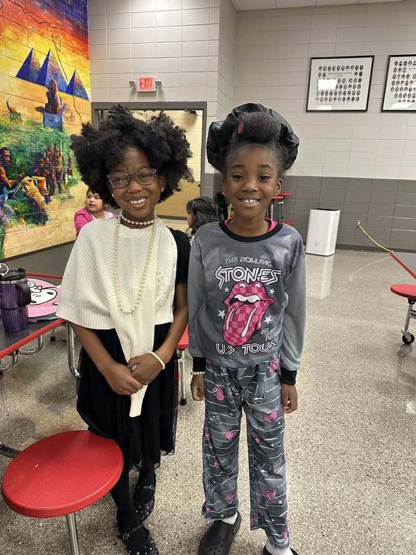 2nd graders, Nailah and Kortney, showing big smiles in the cafeteria with their outfits.