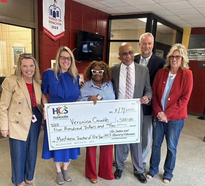 Ms. Caudle holding up  her $500 check with district representatives.
