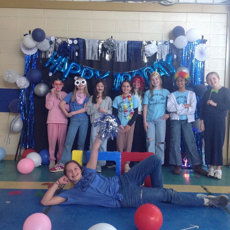 students standing in front of a photo booth celebrating 100