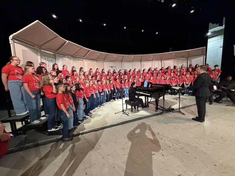 students in state choir standing in red shirts performing in group