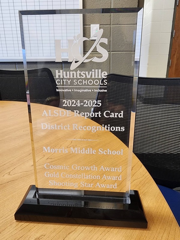A clear lucite plaque witht the words  "Huntsville City Schools 2024-25 ALSDE  Report Card DIstrict Recognition", "Morris Middle School" and "Cosmic Growth Award, Gold Constellation Award and Shootng Star Award"