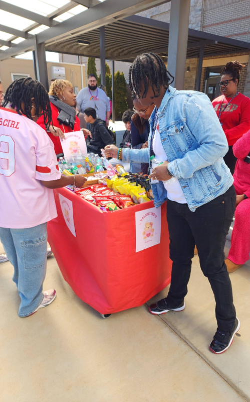 Dr. Burruss rollings a cart full of sweet treats for teachers
