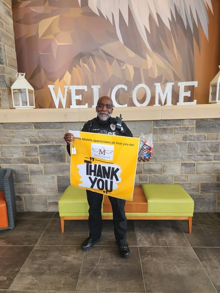 Officer Joseph poses with the poster the students and staff made for him