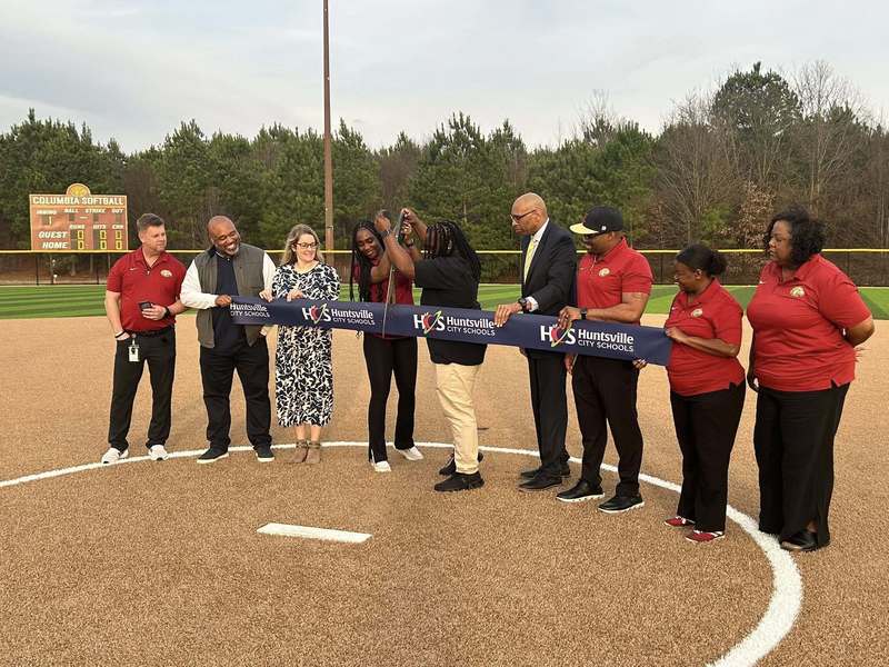 Atletic directors from Columbia  standing with superintendent, and principals cutting ribbon at ceremony for new softball field