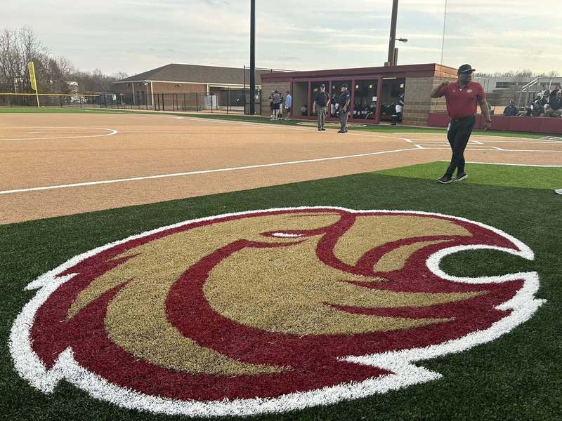 Principal Richey walking on new softball field with red, gold trimmed in white eagle logo in the middle
